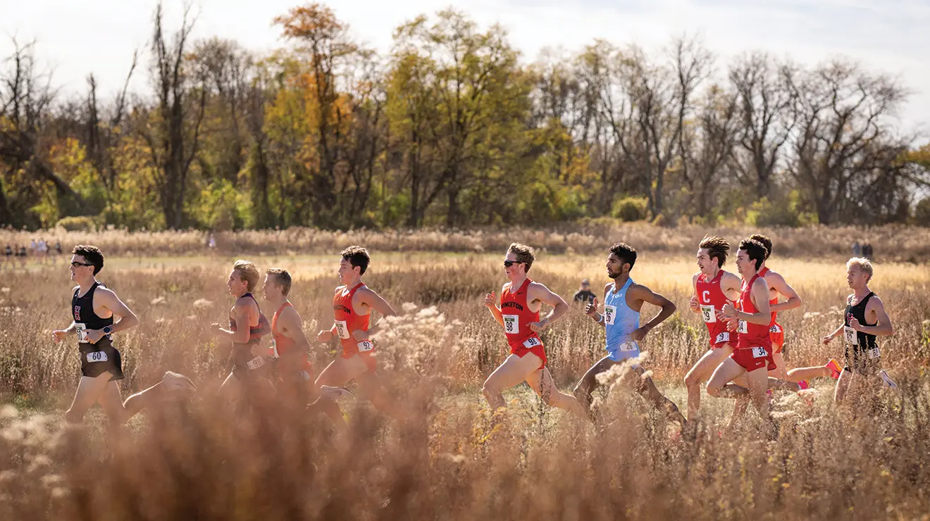 OTC_2024IvyHeptagonal_110224_0034 copy.jpg A track team runs through a field of golden grass.