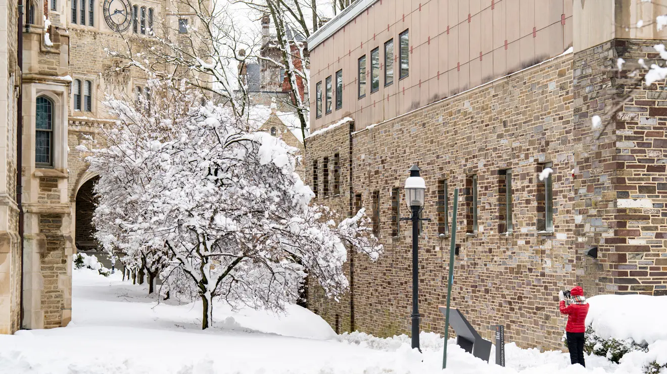 BLIZZARD_Red coat.jpg Student is red coat takes a photo of the snow covered campus after blizzard