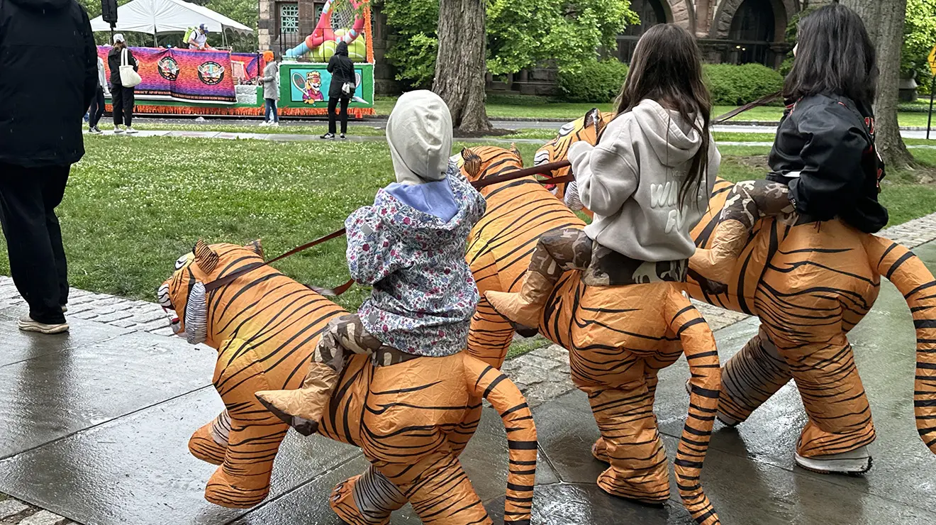 JulieReunions2_cropped.jpg Three children walk in inflatable costumes that look like they're riding on tigers.