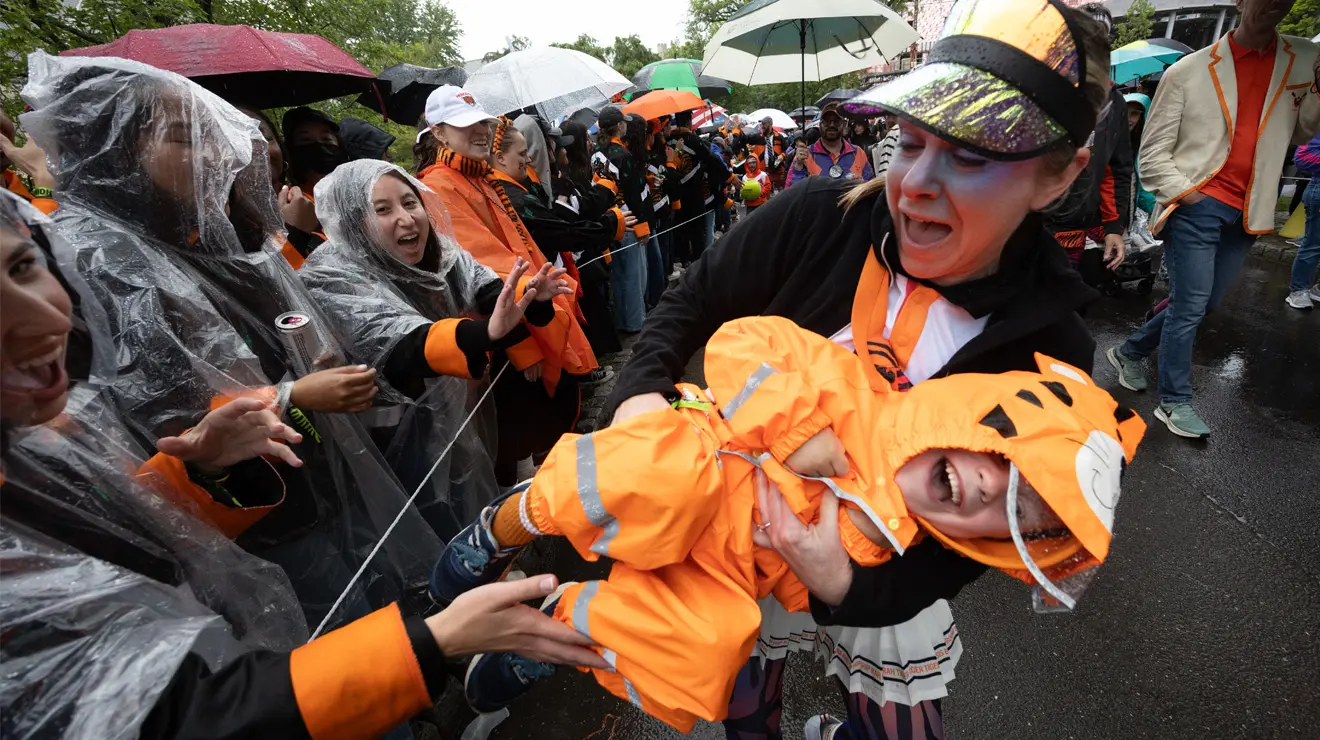 PRADE_Kid having a blast_Kevin Birch.jpg A parent holds a happy but unruly toddler wearing an orange raincoat.