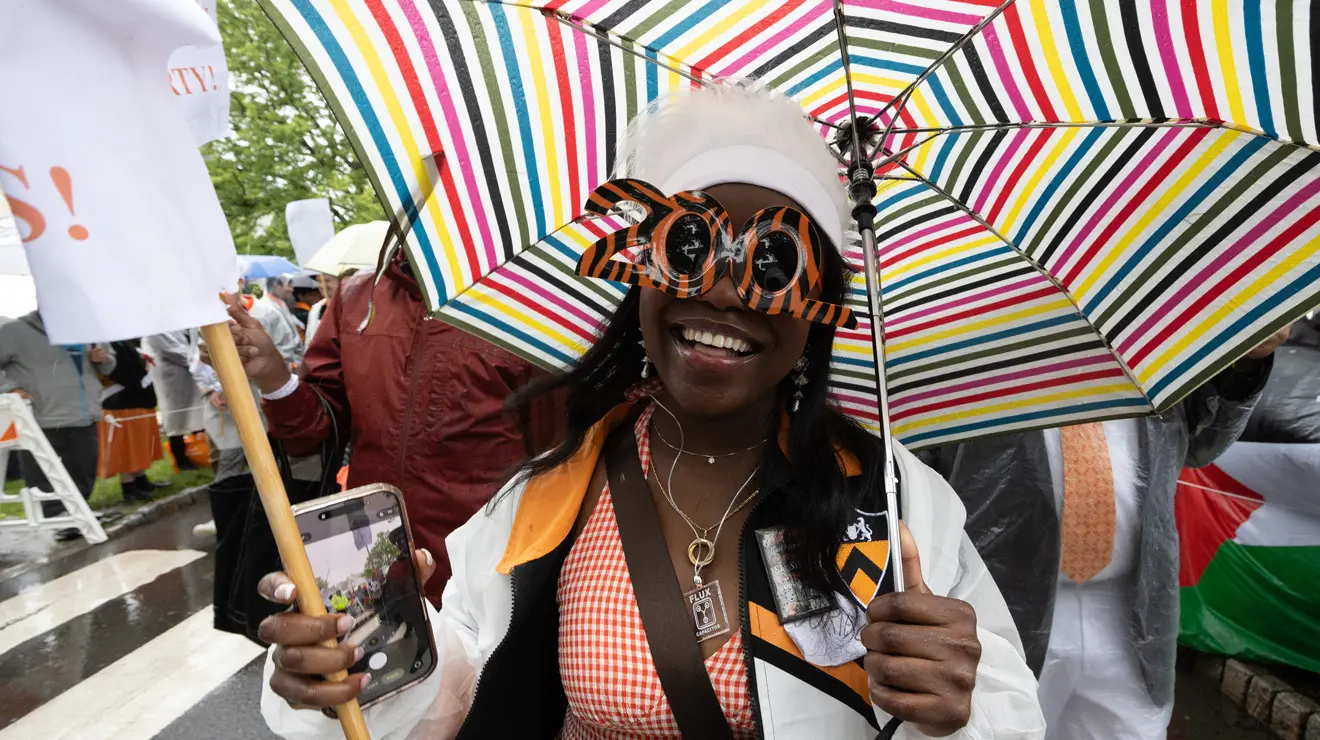 PRADE_Rainbow Umbrella_Kevin Birch.jpg A woman wears tiger-striped sunglasses in the shape of "200."