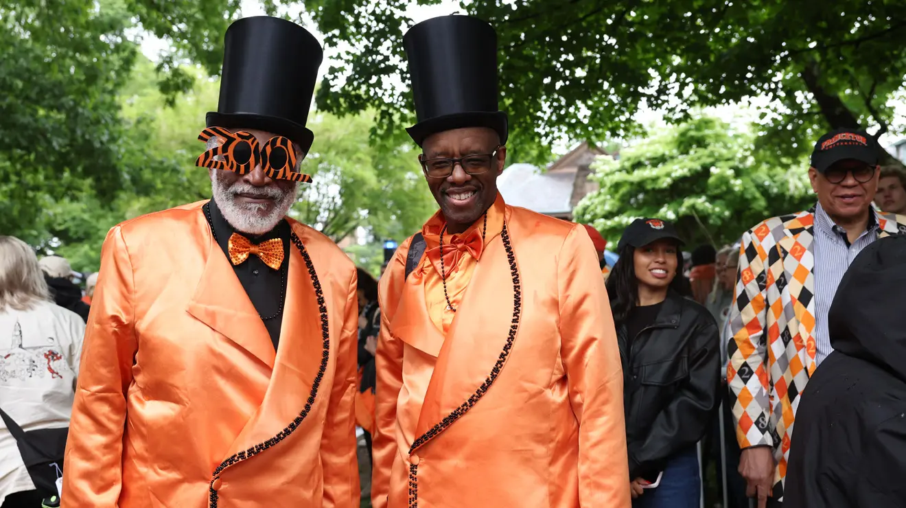 PRADE_Stylish Guys_Bev.jpg Two men wear satiny orange suits and black top hats.